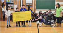 People in the gym while three students hold a large check thumbnail244957